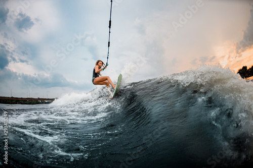 Young girl rides on a wakeboard in the river near forest photo
