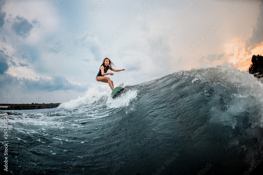 Young girl riding on a wakeboard in the river near forest