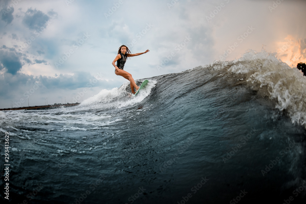 Young girl glides on a wakeboard in the river near forest