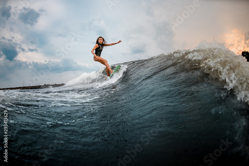 Photography Young girl glides on a wakeboard in the river near forest