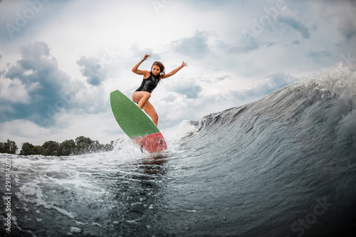 Photography Young girl jumps on a wakeboard in the river near forest