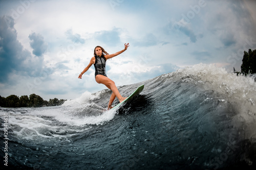 Young girl doing stunts on a wakeboard in the river near forest © fesenko