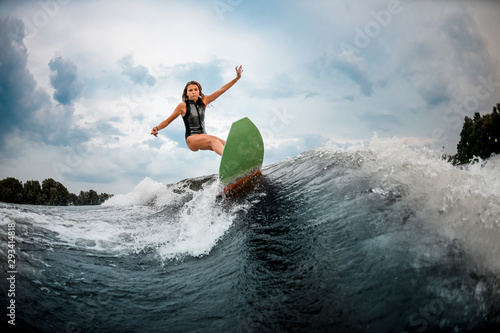 Young girl stunts on a wakeboard in the river near forest