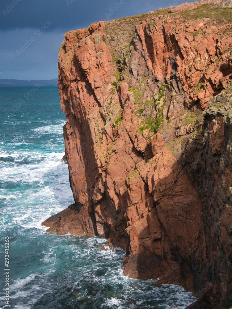 Obraz premium Sea cliffs near North Ham on Muckle Roe, Shetland, UK - the rock is of the Muckle Roe Intrusion - granite, granophyric - igneous bedrock formed in the Devonian Period. 