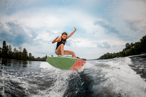 Girl wakesurfer jumping with the surf board