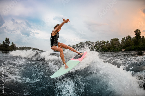 Girl wakesurfer jumping with a surf board