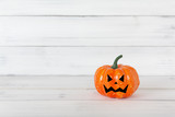 Orange ghost pumpkin on white wood table with copy space.