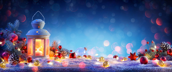 Christmas Lantern On Snowy Table With Fir Branches And Ornaments