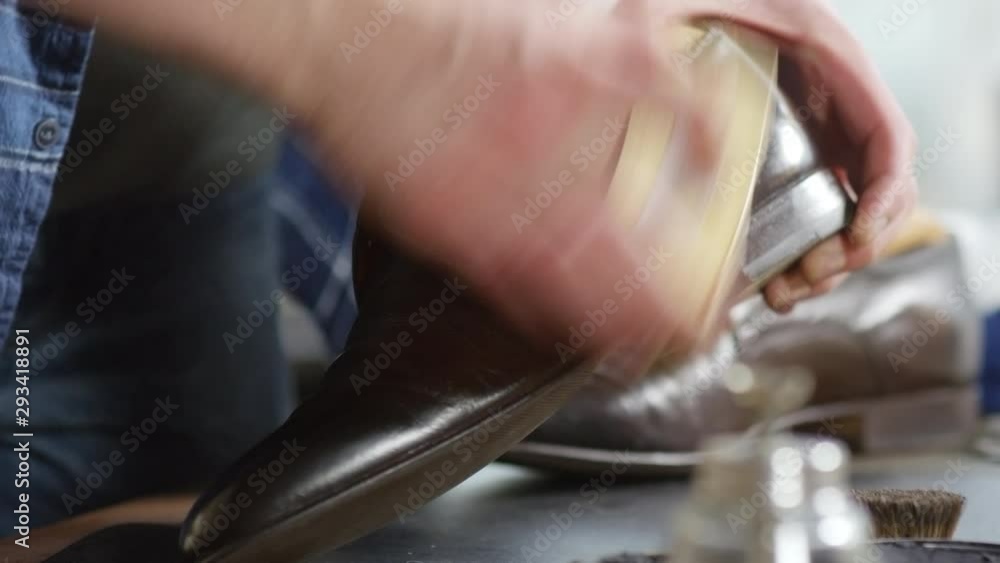 Close up view of hands of unrecognizable shoemaker polishing male leather boot with special brush Close up view of hands of unrecognizable shoemaker polishing male leather boot with special brush