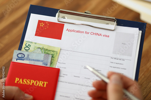 Male hand hold silver pen with passport. Filling China apllication form concept
