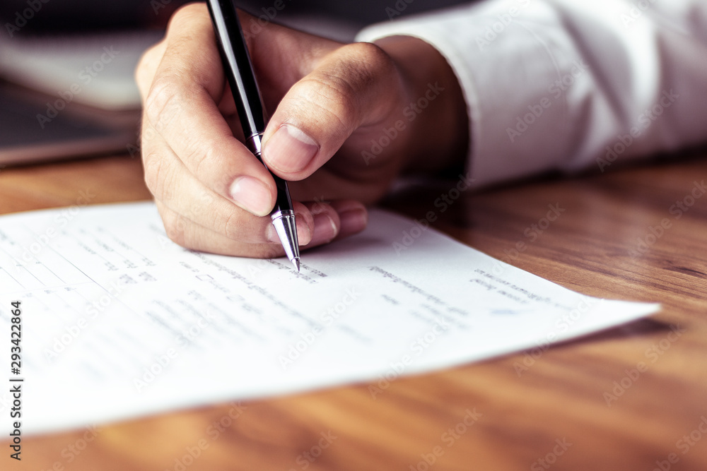 Businessman signing a document after reading the agreement in office Businessman signing a document after reading the agreement in office