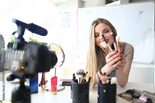 Young Vlogger Talking on Cosmetics Beauty Blog. Pretty Lady Holding Bunch of Makeup Brushes while Recording Video. Gorgeous Woman making Record for Vlog on Cosmetic Product. Tools Selection