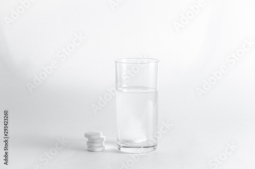 The effervescent tablet dissolves in a glass of water. A stack of drugs isolated on a white background. Treatment of viral diseases. Help with depression and insomnia. Liquid multivitamins