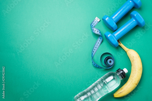 Bananas, dumbbells, a tape for measuring the waist, a horse with water on a green background, top view