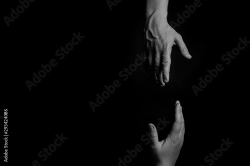 Helping Hand, Hand reaching, trying to pull up and rescue, black background, copy space