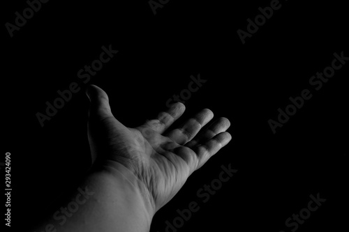 Hand palm up reaching out, isolated on black background, giving a helping hand. Give me your hand, let me help you.