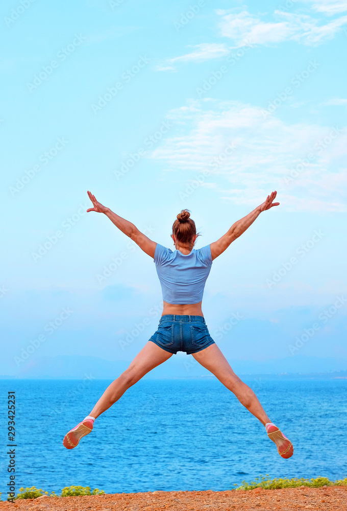 sporty young girl jumps easily on the beach in summer sporty young girl jumps easily on the beach in summer