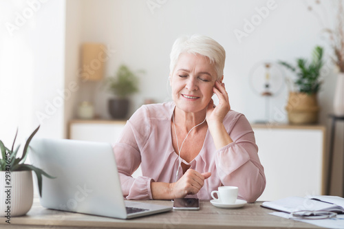 Aged business woman with earphones enjoying music