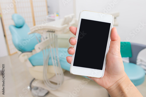 Smart phone with  black screen in hand on blurred in dentist Office background