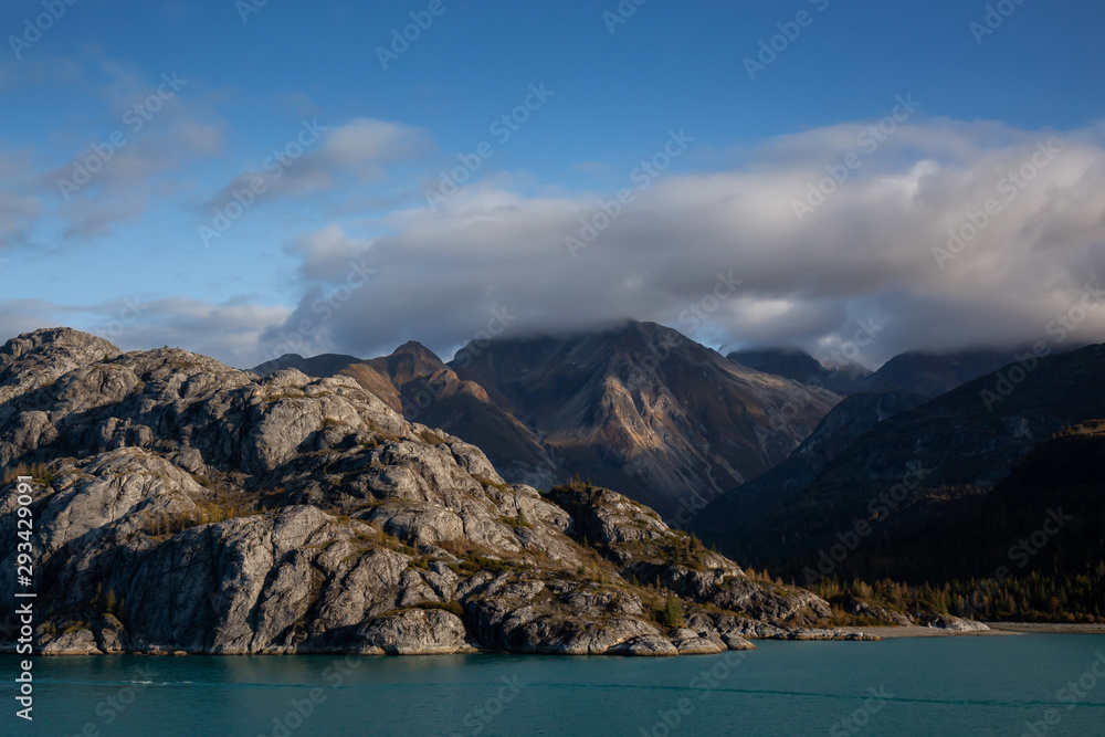 Beautiful View of American Mountain Landscape on the Ocean Coast during a cloudy and colorful morning in fall season. Taken in Glacier Bay National Park and Preserve, Alaska, USA.