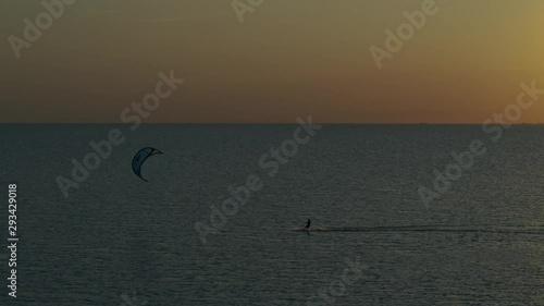 A man kitesurfing in the sea at sunset. Shooting from a height