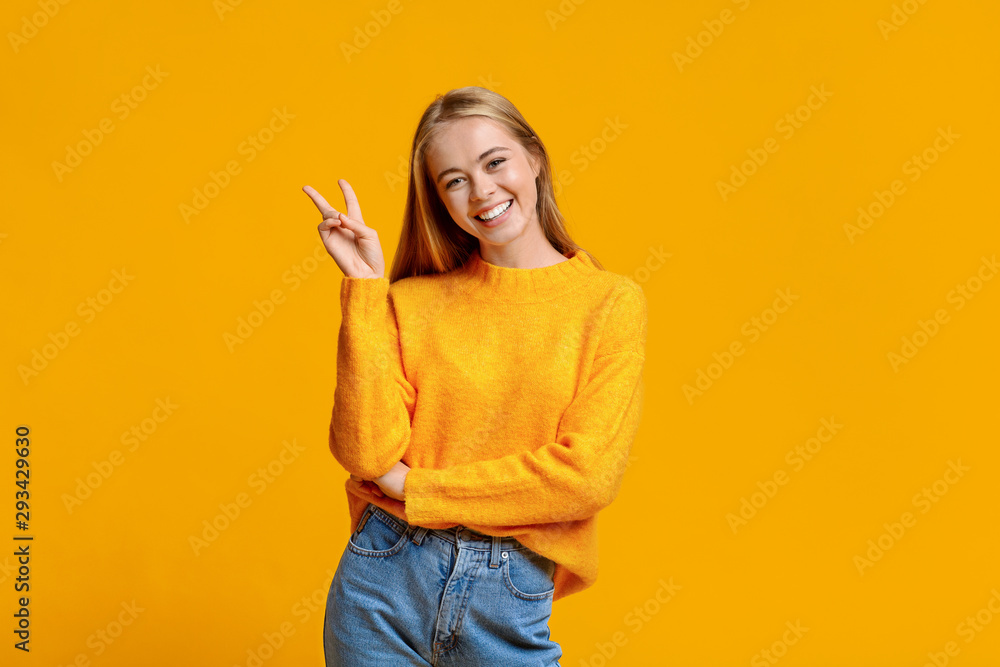 Cherful teen girl showing v-sign posing to camera Cherful teen girl showing v-sign posing to camera