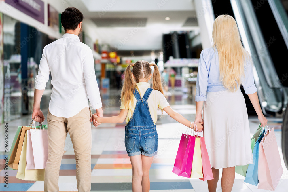 Unrecognizable Parents And Daughter Walking In Shopping Mall, Back View Unrecognizable Parents And Daughter Walking In Shopping Mall, Back View