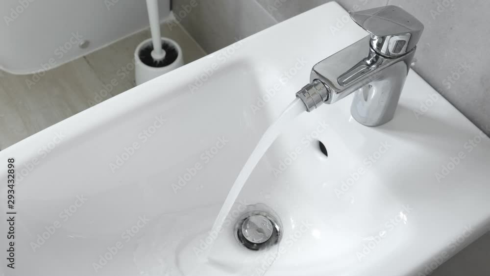 White ceramic bidet at modern restroom interior. Water is running. Nobody