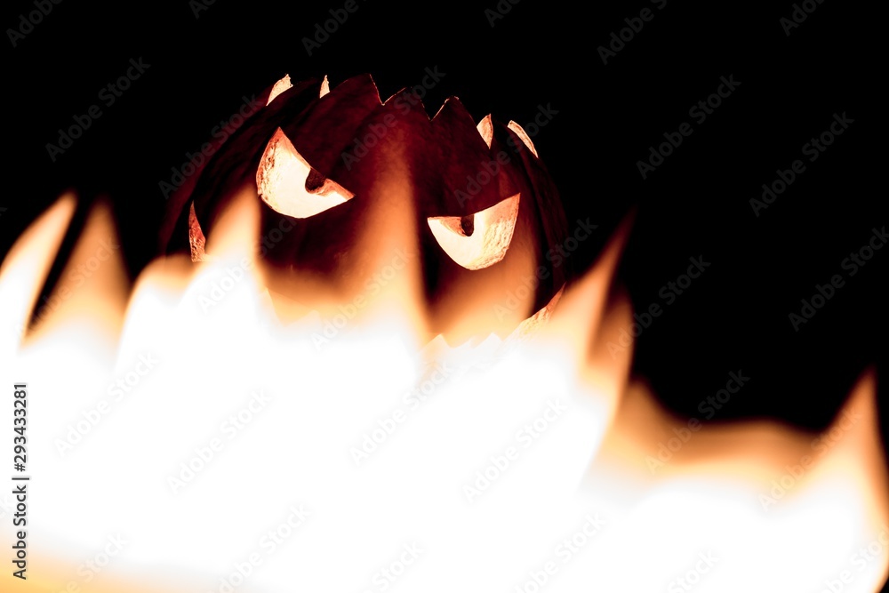 Spooky smiling halloween pumpkin in hot burning hell fire flames. The big helloween symbol has a mad face glowing eyes and also a glow in its mouth and teeth. Black orange nightmare of October 31st Spooky smiling halloween pumpkin in hot burning hell fire flames. The big helloween symbol has a mad face glowing eyes and also a glow in its mouth and teeth. Black orange nightmare of October 31st