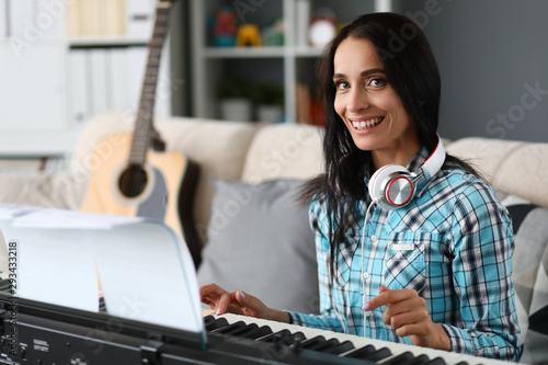 Beautiful woman playing piano on background apartment. Home recording studio concept