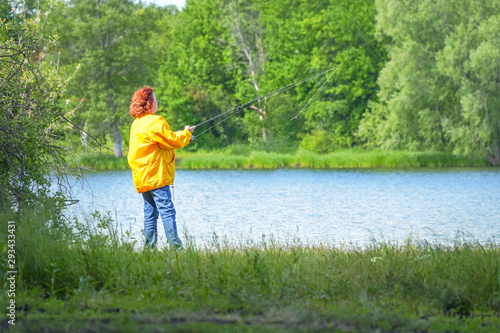 Woman in yellow jacket fishing spinning on the lake