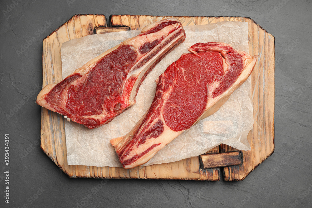 Wooden board with raw beef meat on black table, flat lay Wooden board with raw beef meat on black table, flat lay