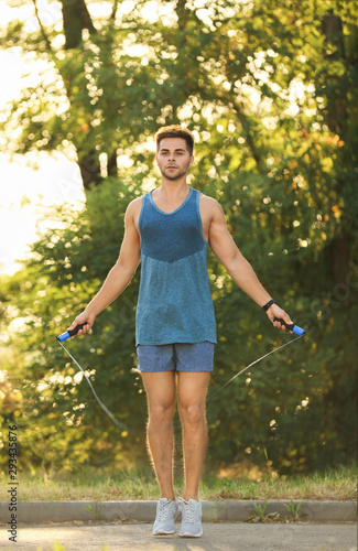 Young man training with jump rope in park