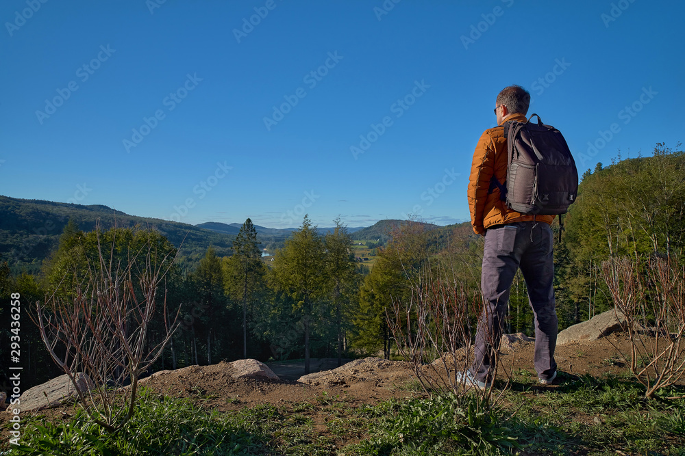 30 year old man resting outdoors in the mountains, standing far on the trail, looking into the distance in a forest, in Quebec Harrington. Travel to Canada 30 year old man resting outdoors in the mountains, standing far on the trail, looking into the distance in a forest, in Quebec Harrington. Travel to Canada