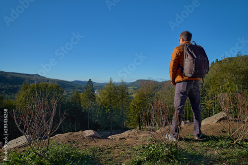 30 year old man resting outdoors in the mountains  standing far on the trail  looking into the distance in a forest  in Quebec Harrington. Travel to Canada