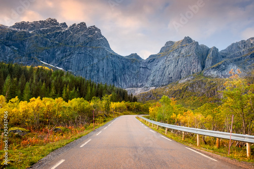a beautiful road to the fishing town of Nusfjord, Norway, Lofoten Islands, golden autumn at the rocky wall of the mountains.