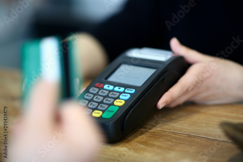 Customer paying with credit card via payment terminal at cash desk background concept