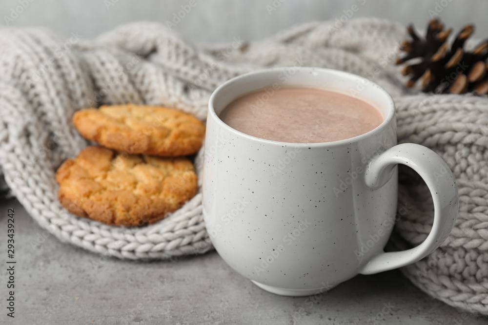 Delicious hot cocoa drink in cup, cookies and knitted blanket on grey surface Delicious hot cocoa drink in cup, cookies and knitted blanket on grey surface