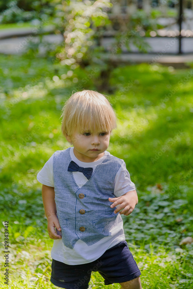 Happy little boy on a green lawn in a park. Happy little boy on a green lawn in a park.