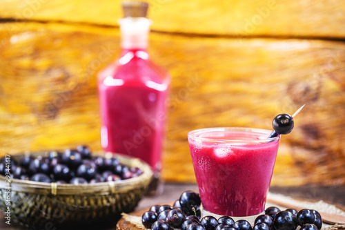 Organic Brazilian home made juice made with the fruit known as jabuticaba or jaboticaba. Juice of purple color on rustic wooden background. Fruit of the October season. photo