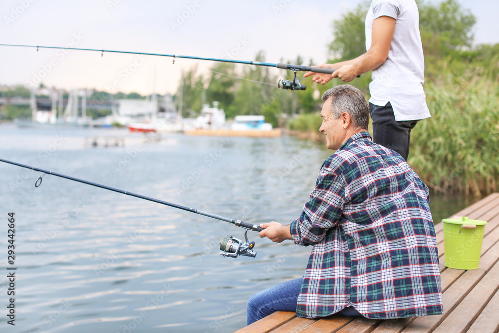 Young man and his father fishing on river Young man and his father fishing on river