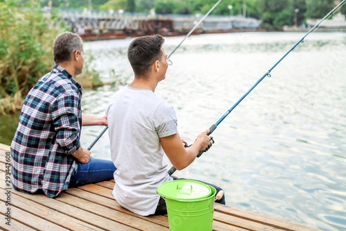 Young man and his father fishing on river