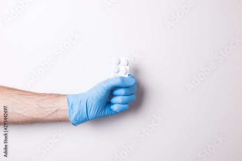 \hand in glove, hand hold the pills on white background