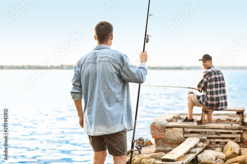 Young man and his father fishing on river