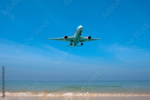 An airplane lands on a flight flying over Mai Khao Beach in Thailand.