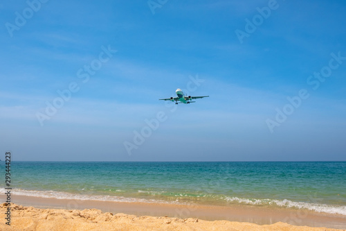 The plane comes in for landing flying over a beautiful tropical beach with fine sand and blue sea. © terezika