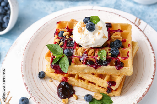 Tasty waffles, ice cream and blueberries on plate