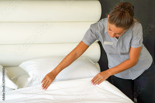 Maid making bed in hotel room. Housekeeper Making Bed