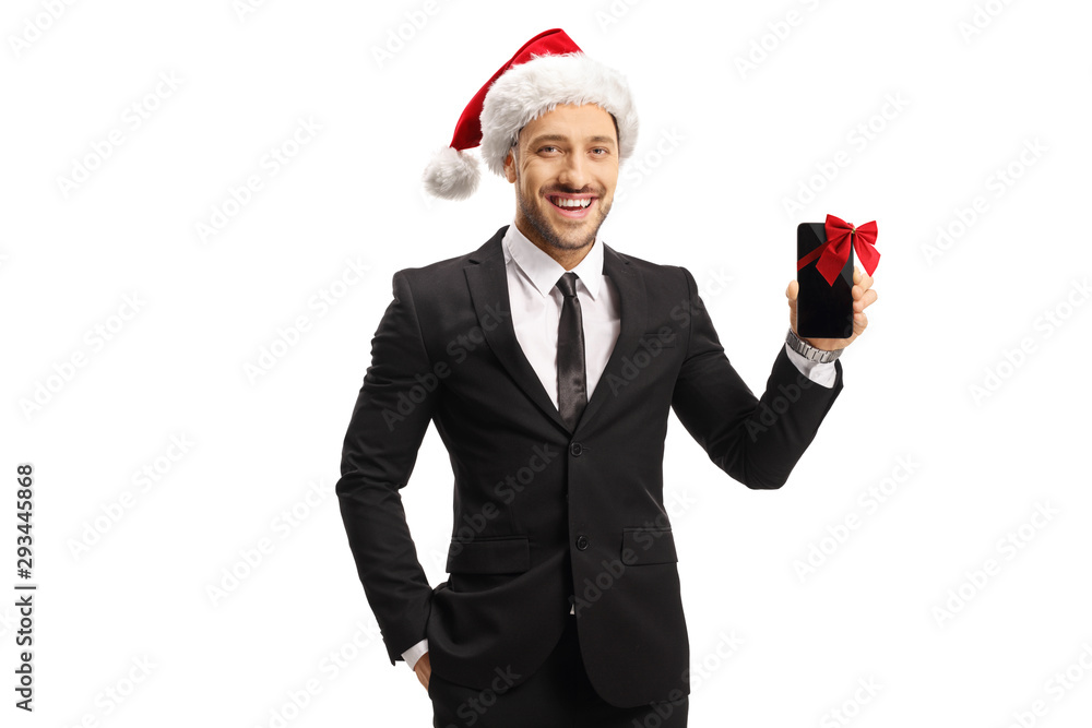 Cheerful man in a suit and a santa claus hat holding a mobile phone for a present Cheerful man in a suit and a santa claus hat holding a mobile phone for a present