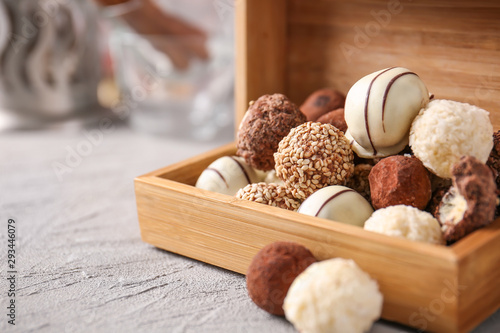 Box with tasty sweet truffles on grey table